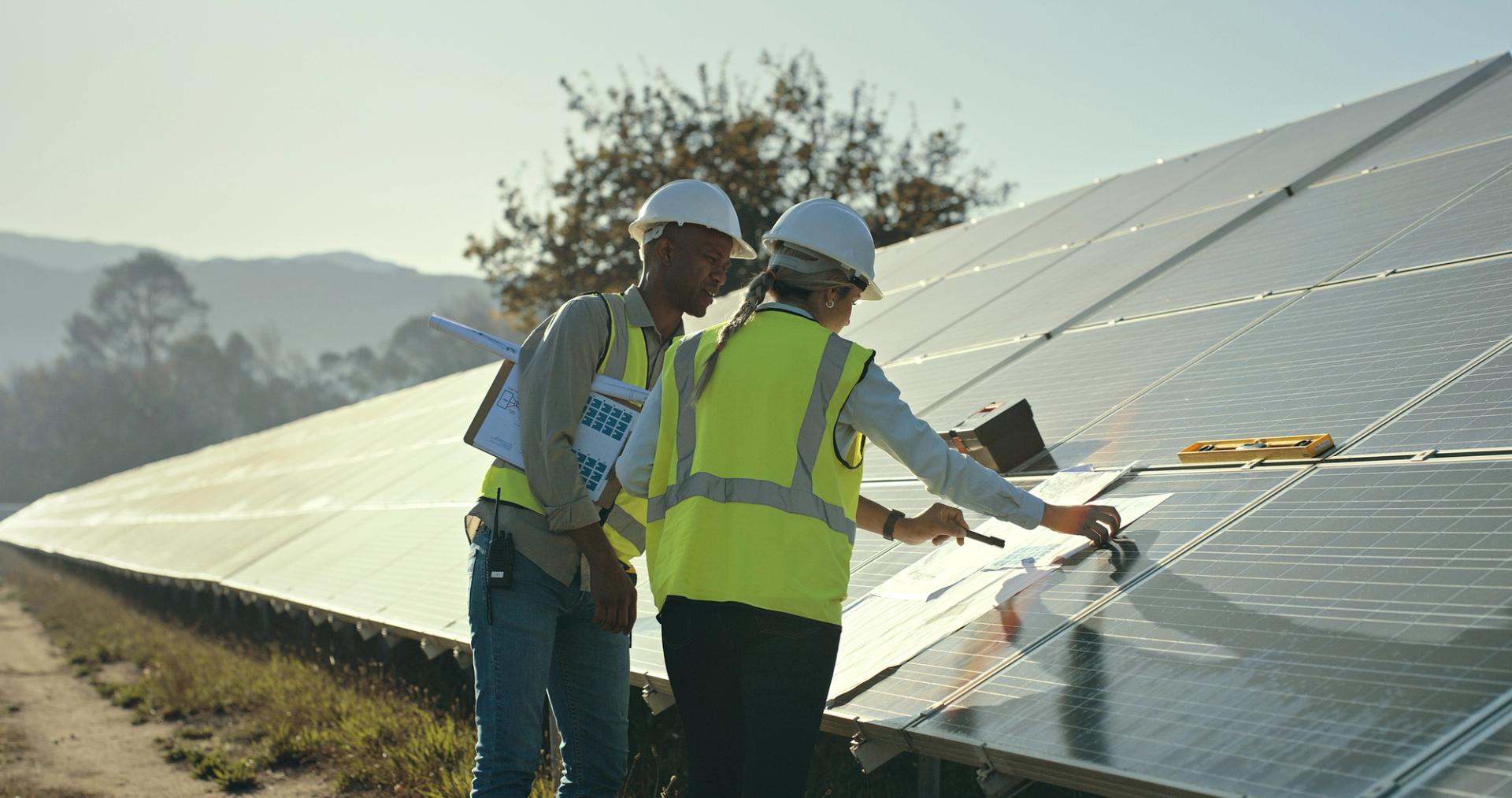 Infrastructure engineers reviewing plans at a UK solar energy project site.