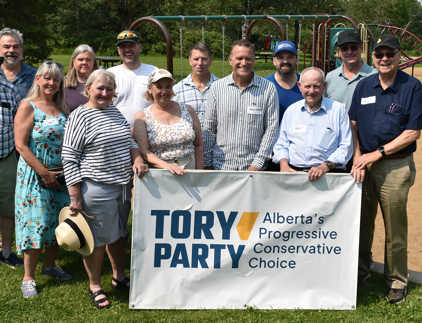 Tory Party members and supporters standing together with a party banner