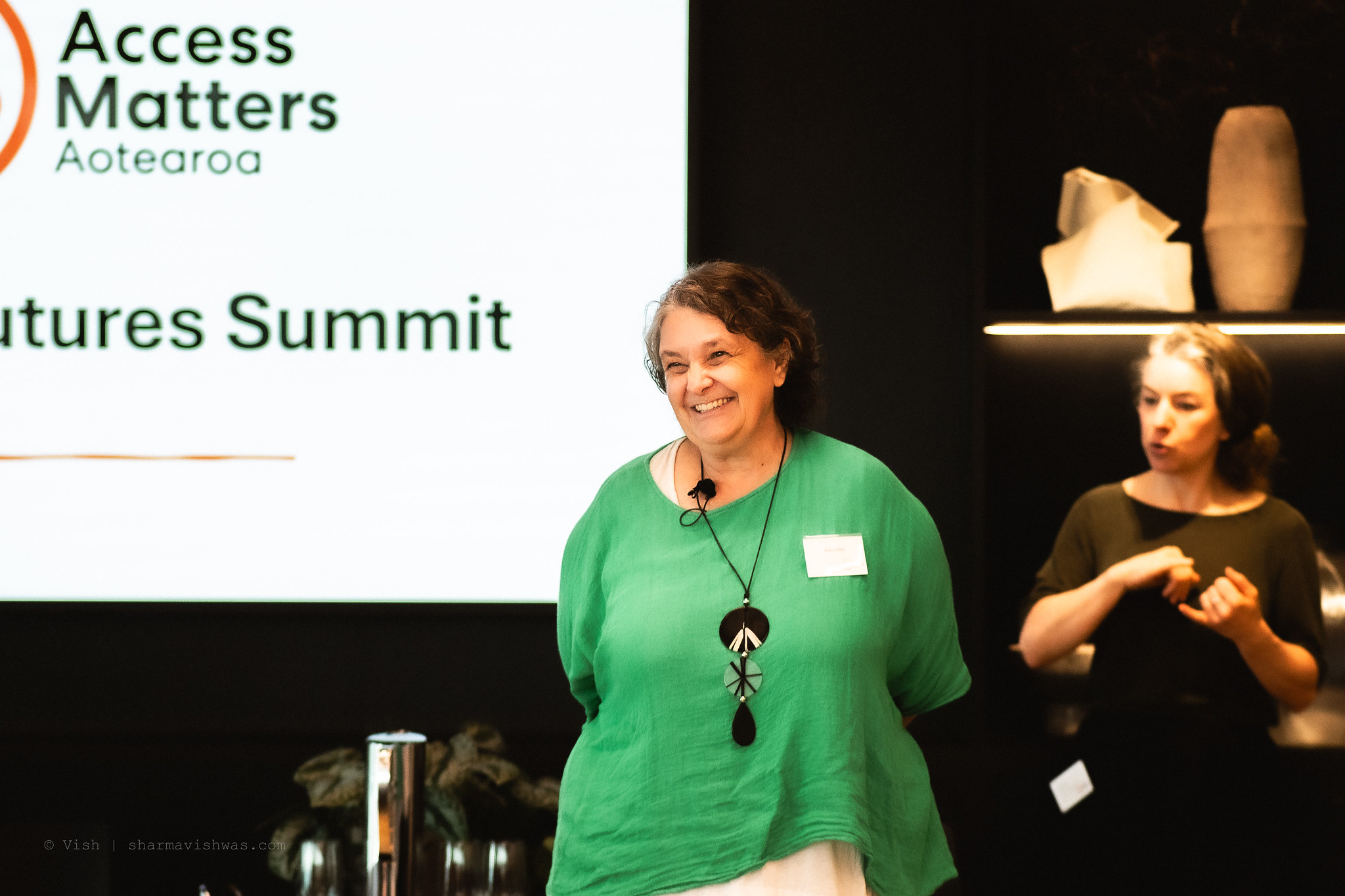 Dr Susan Gee MC at Accessible Futures Summit 2026 with NZSL interpreter