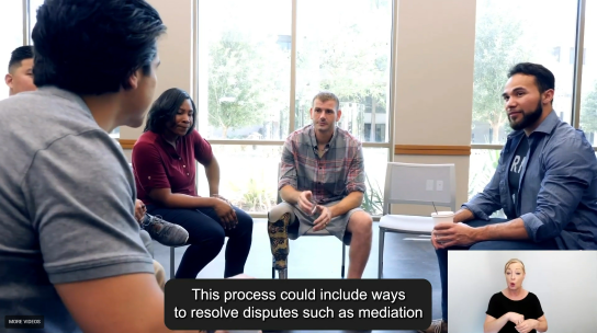 Screenshot from Amy Hogan video showing a group discussion centred around a man with a prosthetic leg sml