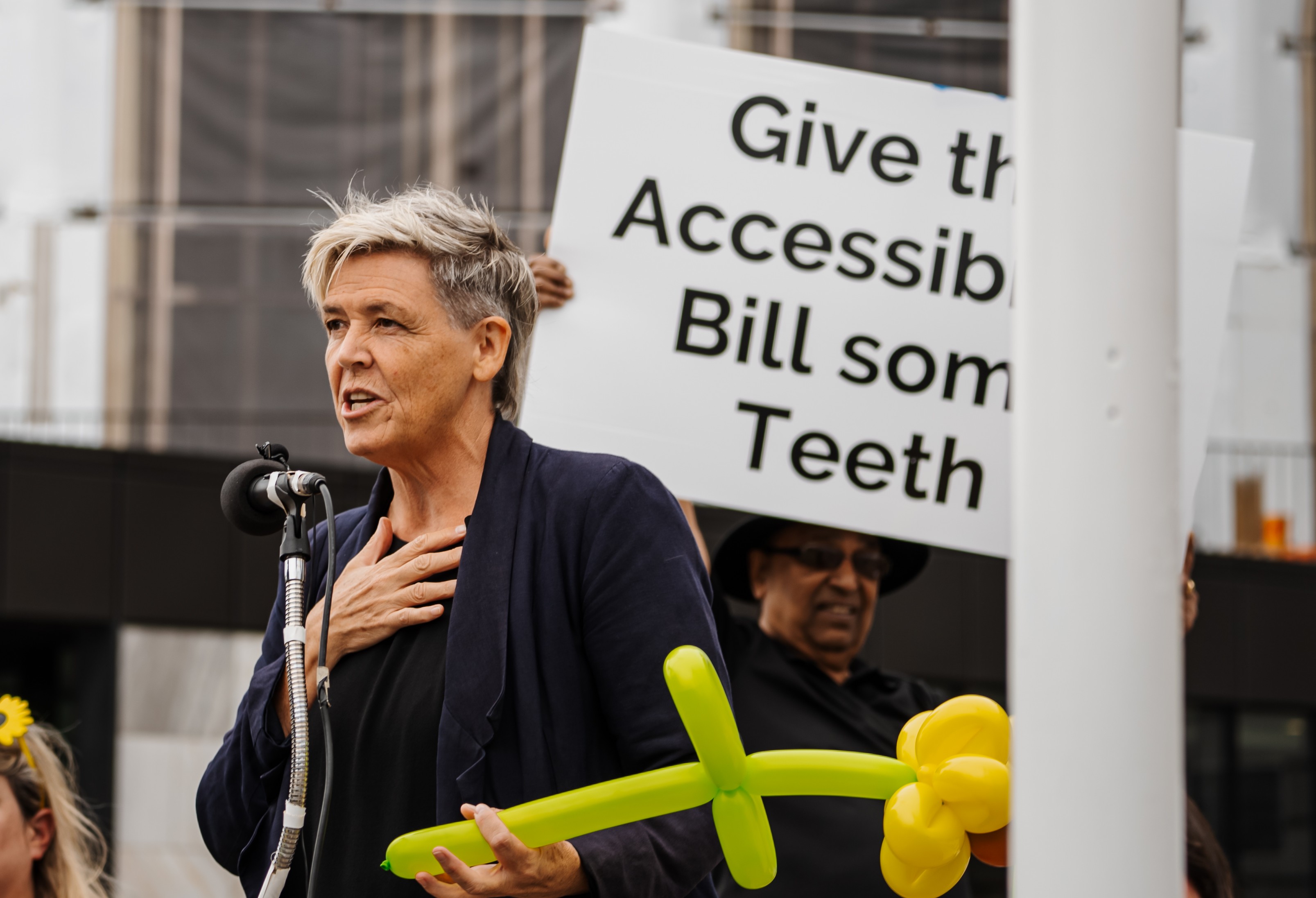 Jan Logie MP holding sunflower balloon speaking at petition presentation 2023 crop