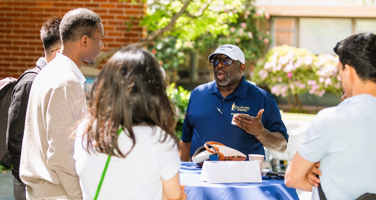 Ahmad wearing a Cal alumni shirt and speaking to young people