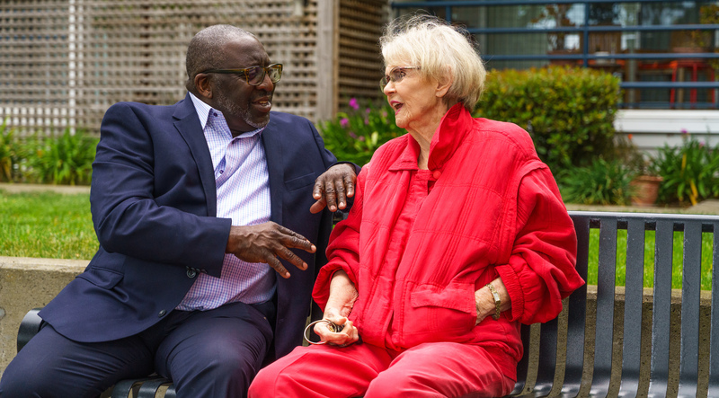 Ahmad and a woman sitting on a bench and talking