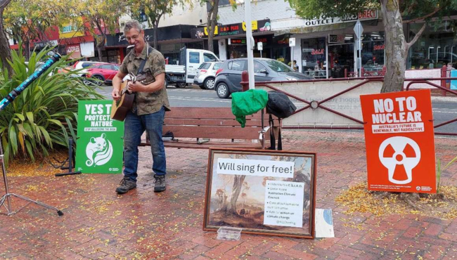 Man busking on guitar on street.