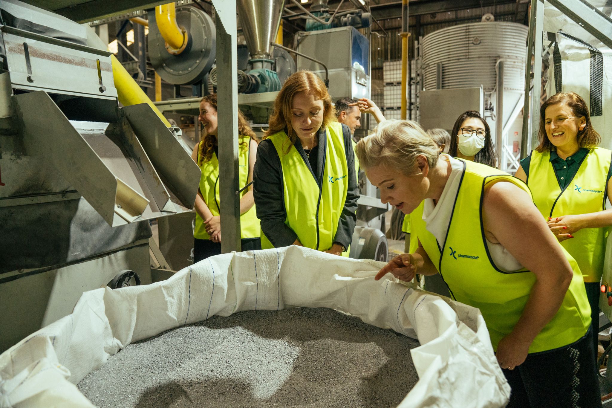 People peer into a vat of plastic pellets