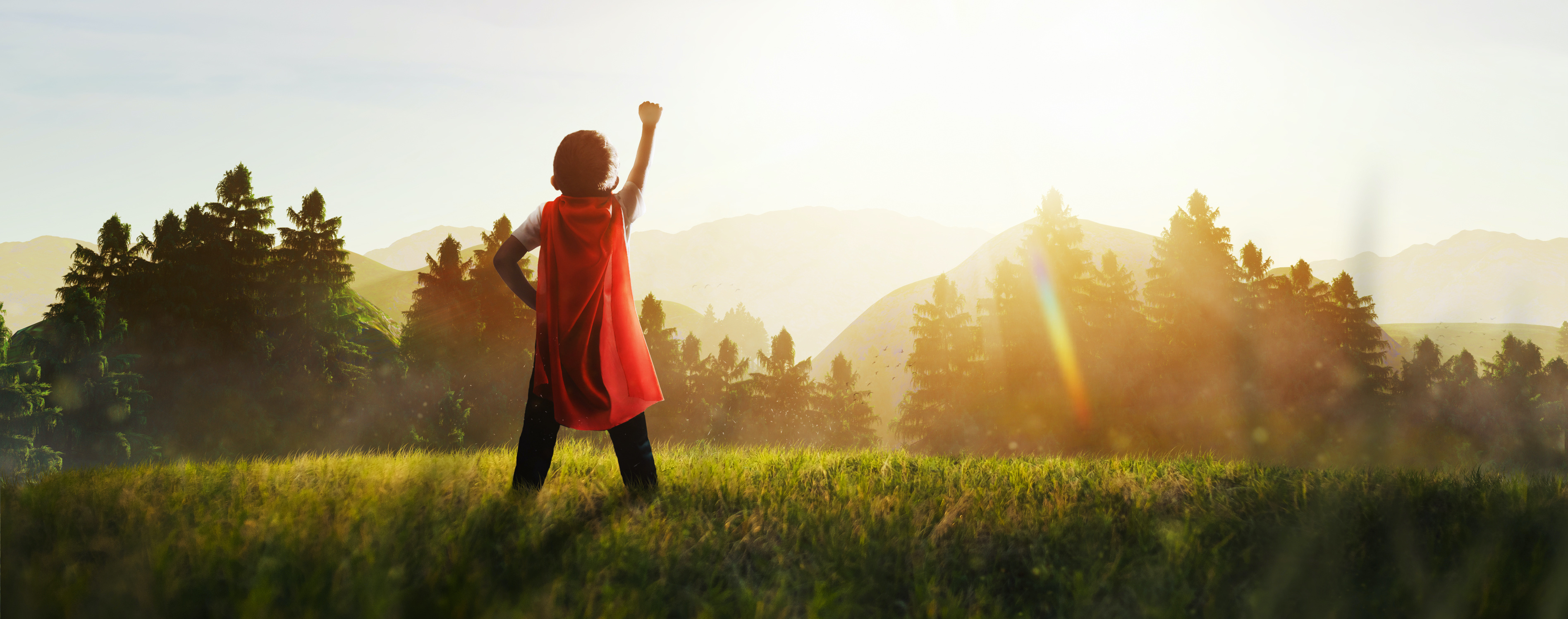 A child raising their hand against a mountain landscape