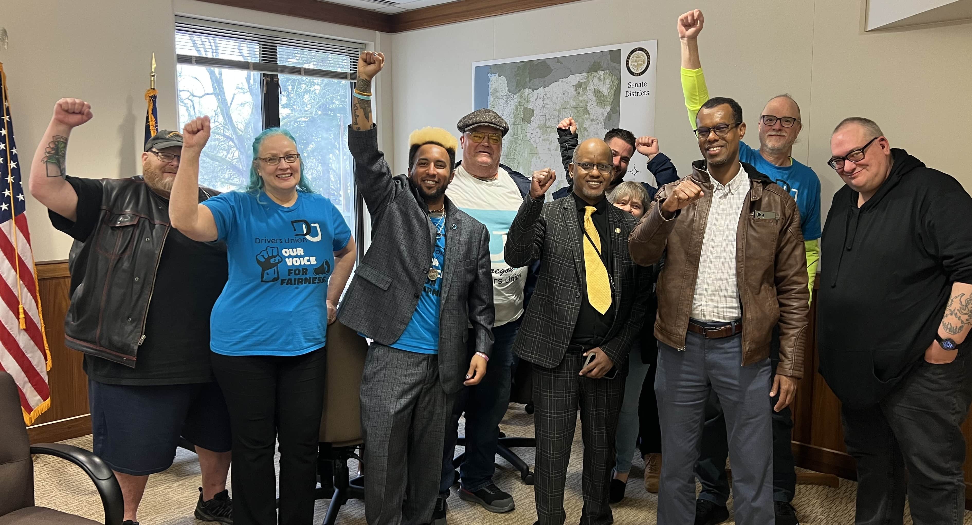A group of drivers in an Oregon Senate office with Senator Kayse Jama in center