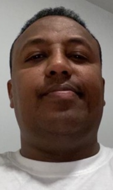 A person in a white tshirt smiles into the camera