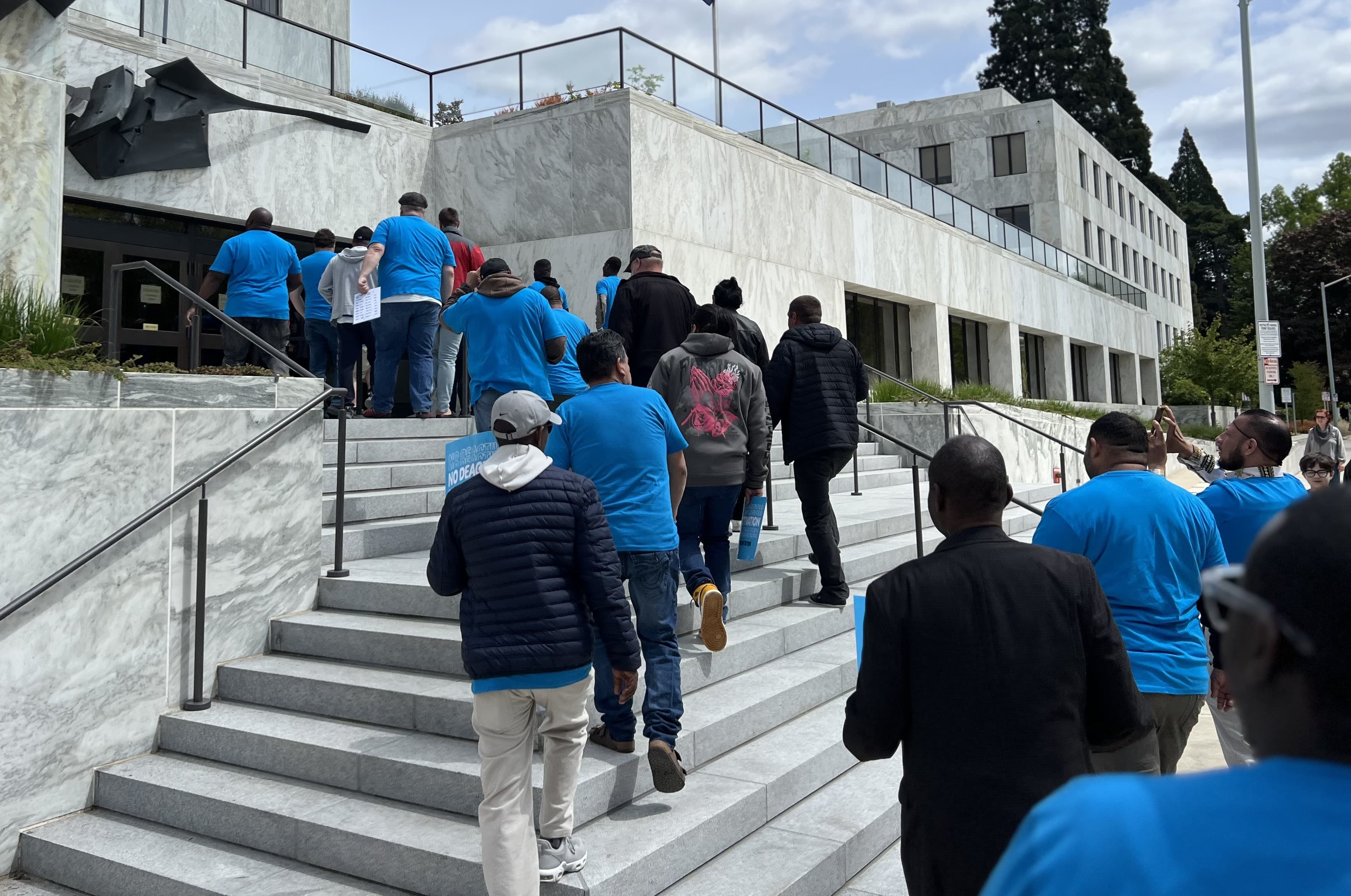 A line of drivers walks up the steps of the Oregon State Capitol building