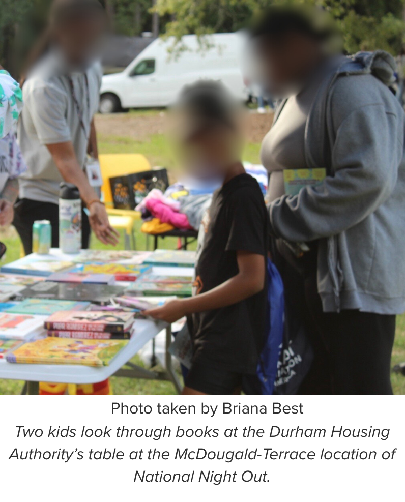 Two kids look through books at the Durham Housing Authority’s table at the McDougald-Terrace location of National Night Out.