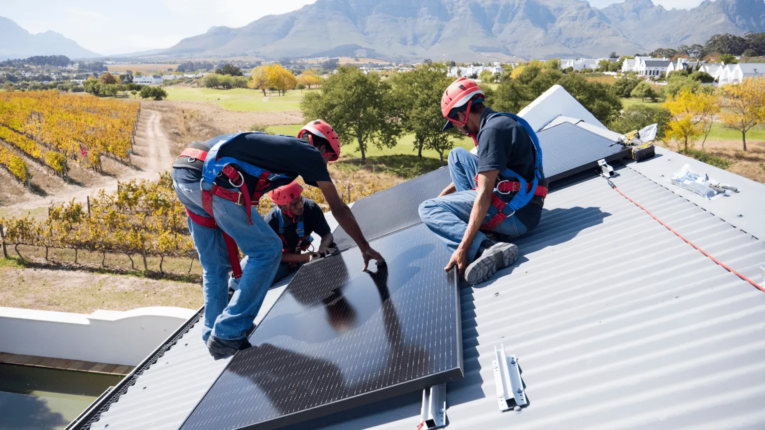 two workers  installing solar pannels on a
roof