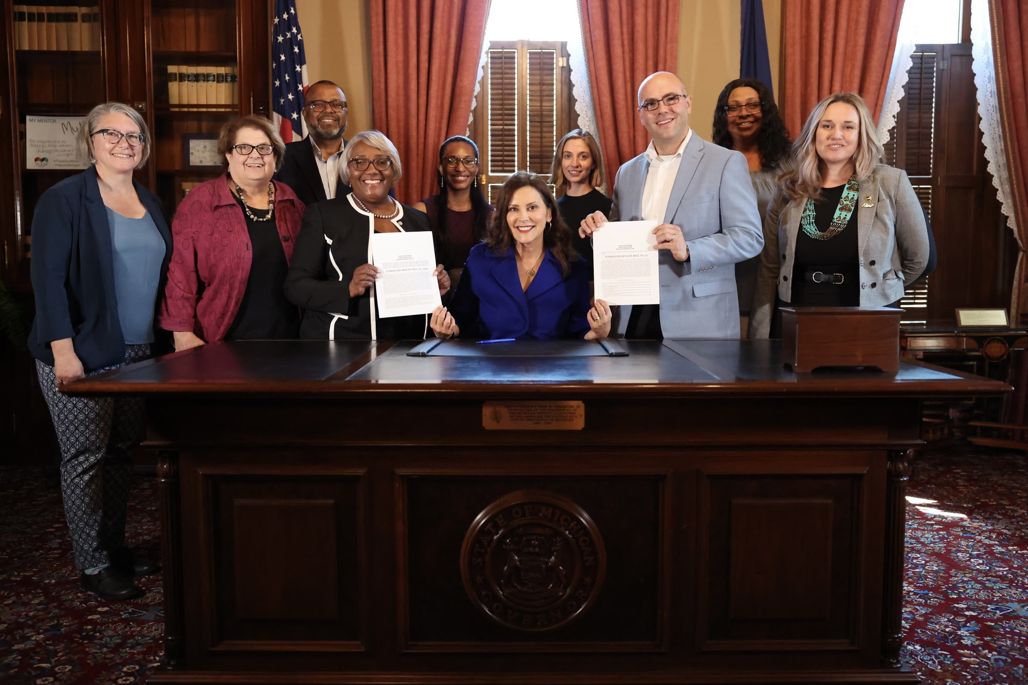 Lead poisoning prevention advocates pose with Gov. Gretchen Whitmer after she signs universal lead testing into law.