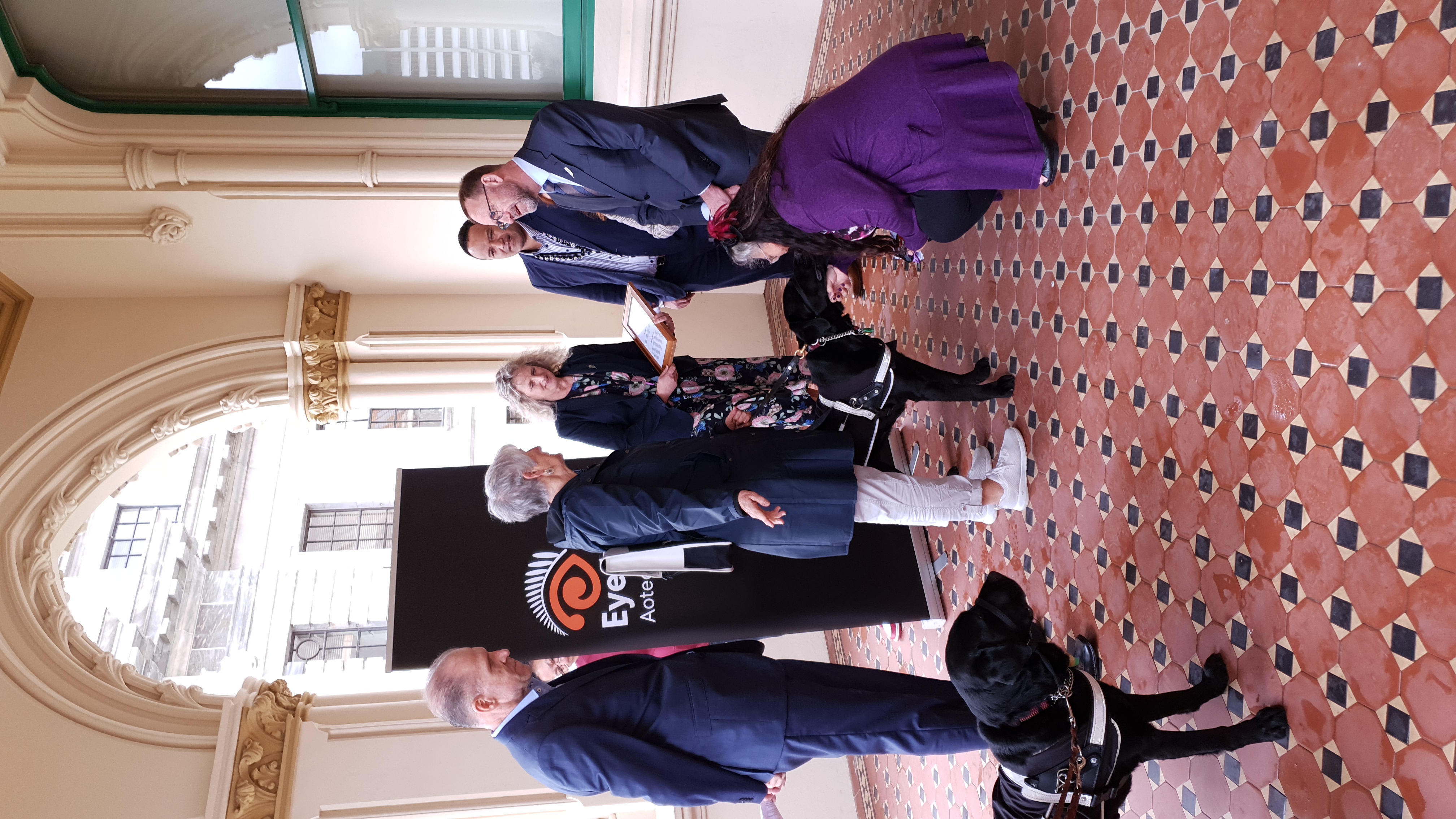 Eye Health Aotearoa representatives, two guide dogs, NZ politicians, with EHA banner.