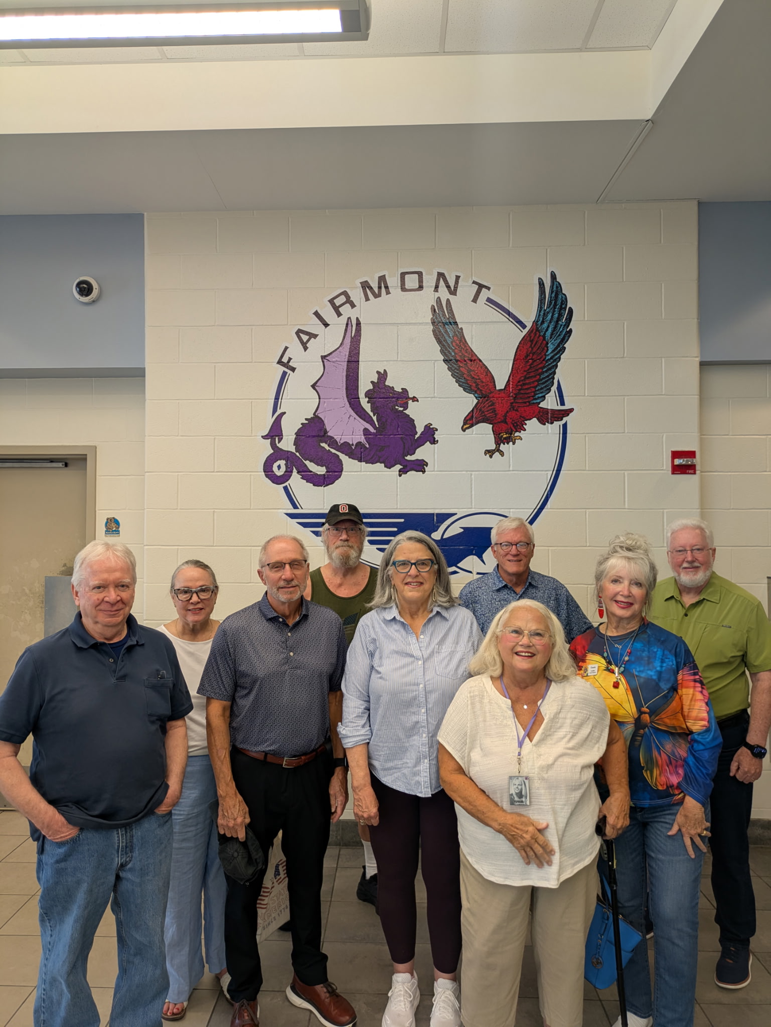 Group of 1971 Fairmont West Dragons gathers in front of hall of fame logo for their 55th high school reunion