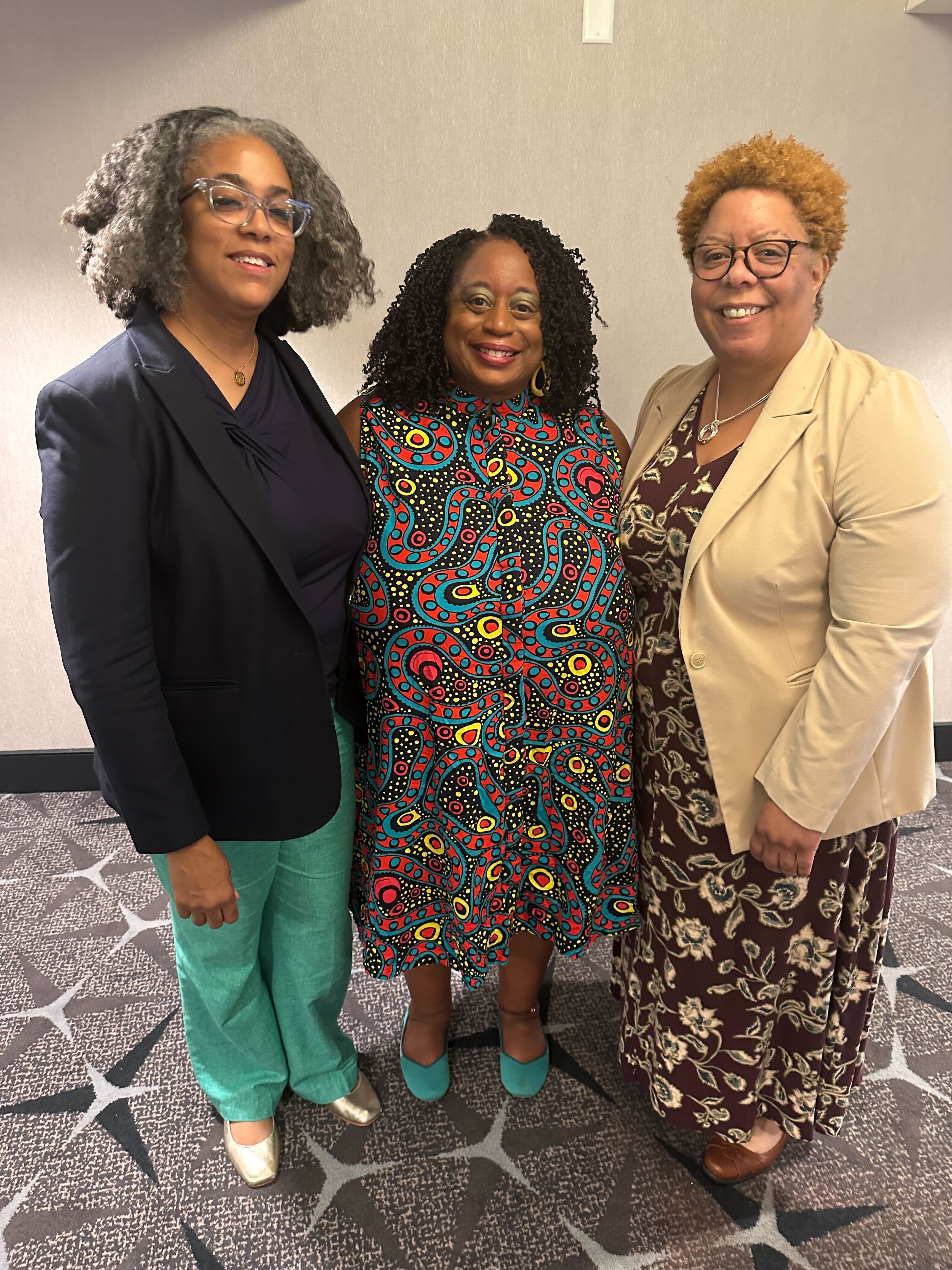Three black women pose for a picture smiling