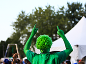 Photo of Harvest Picnic performer clad in all green, pointing to sky