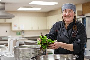 Photo - Mary Weiler, hospitality teacher at St. James Catholic High School, cooking in the cafeteria