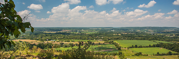 view of farmers fields and forests from a hill