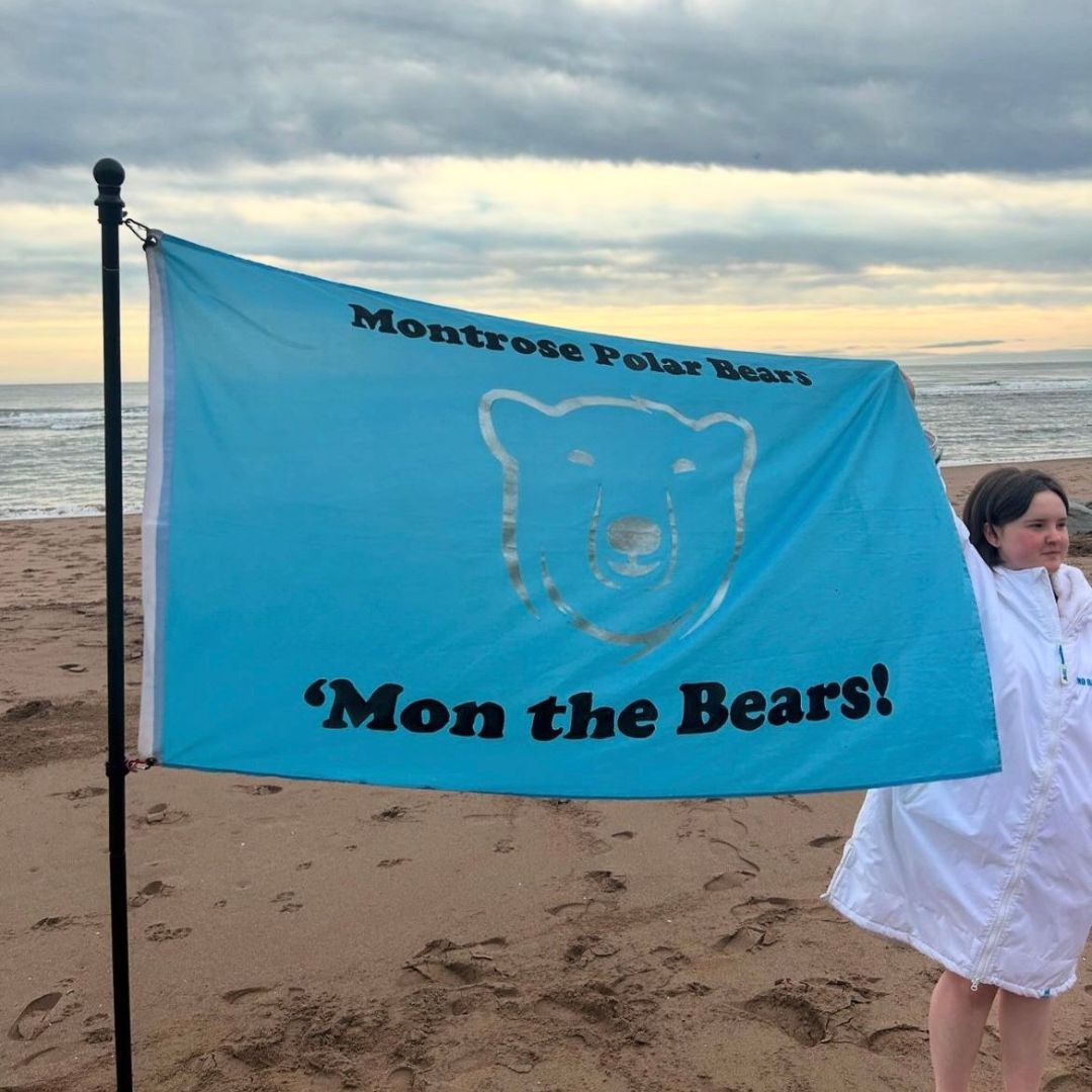 A young girl holds up a blue flag that reads "mon the bears"