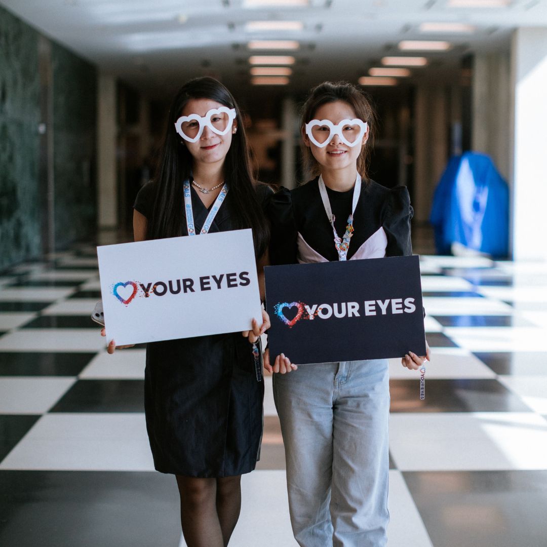 2 women wearing heart glasses, stand holding
Love Your Eyes Signs. 
