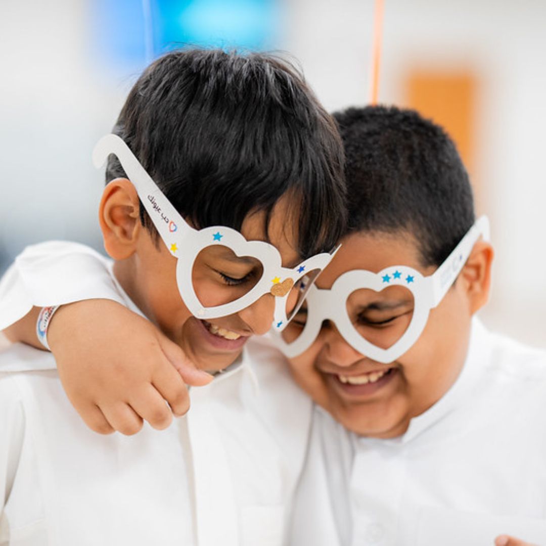 Two boys, wearing heart glasses smiling