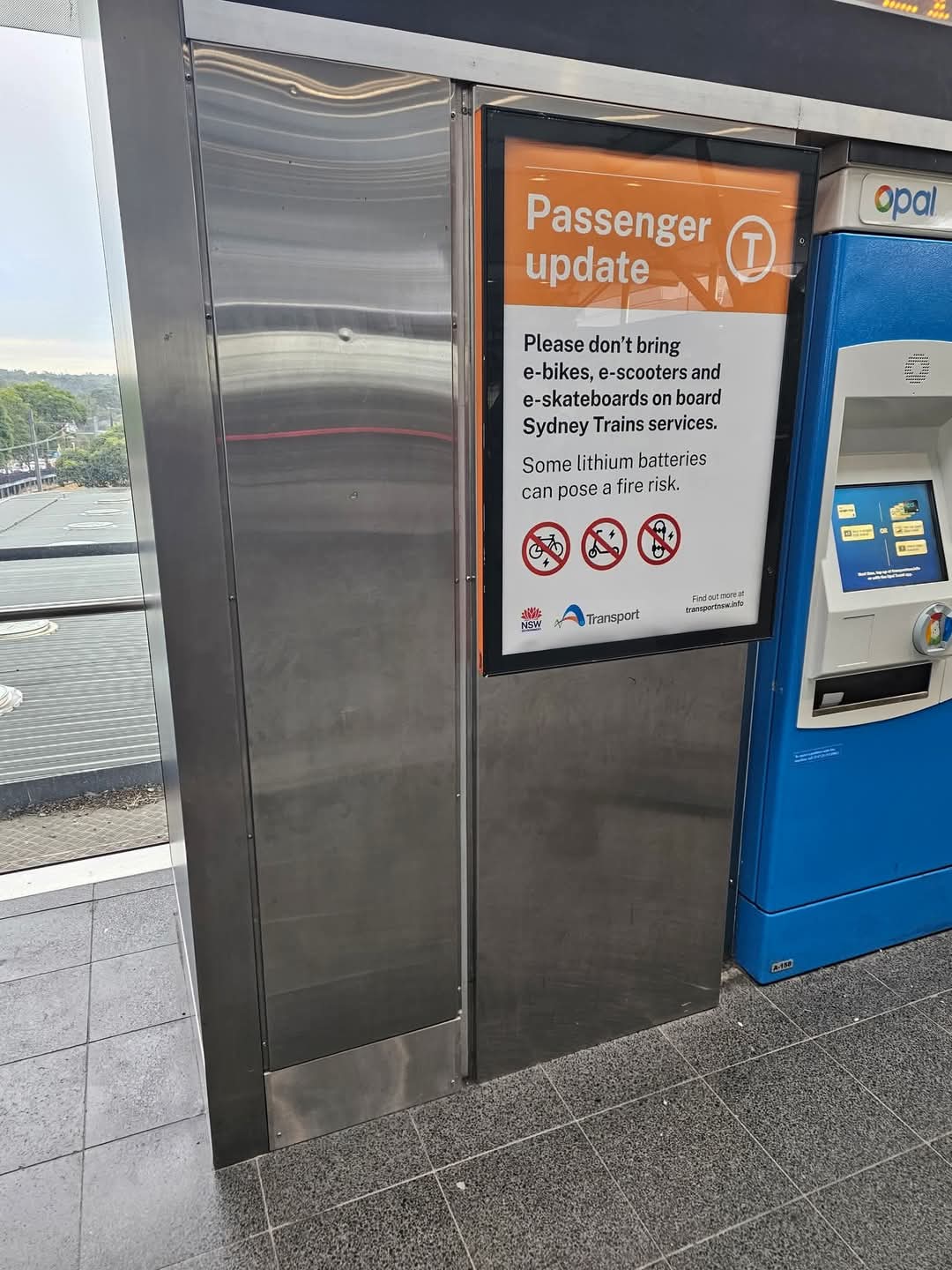 Poster reads "Passenger update Please don't bring e-bikes, e-scooters and e-skateboards on board Sydney Trains services. Some lithium batteries can pose a fire risk."