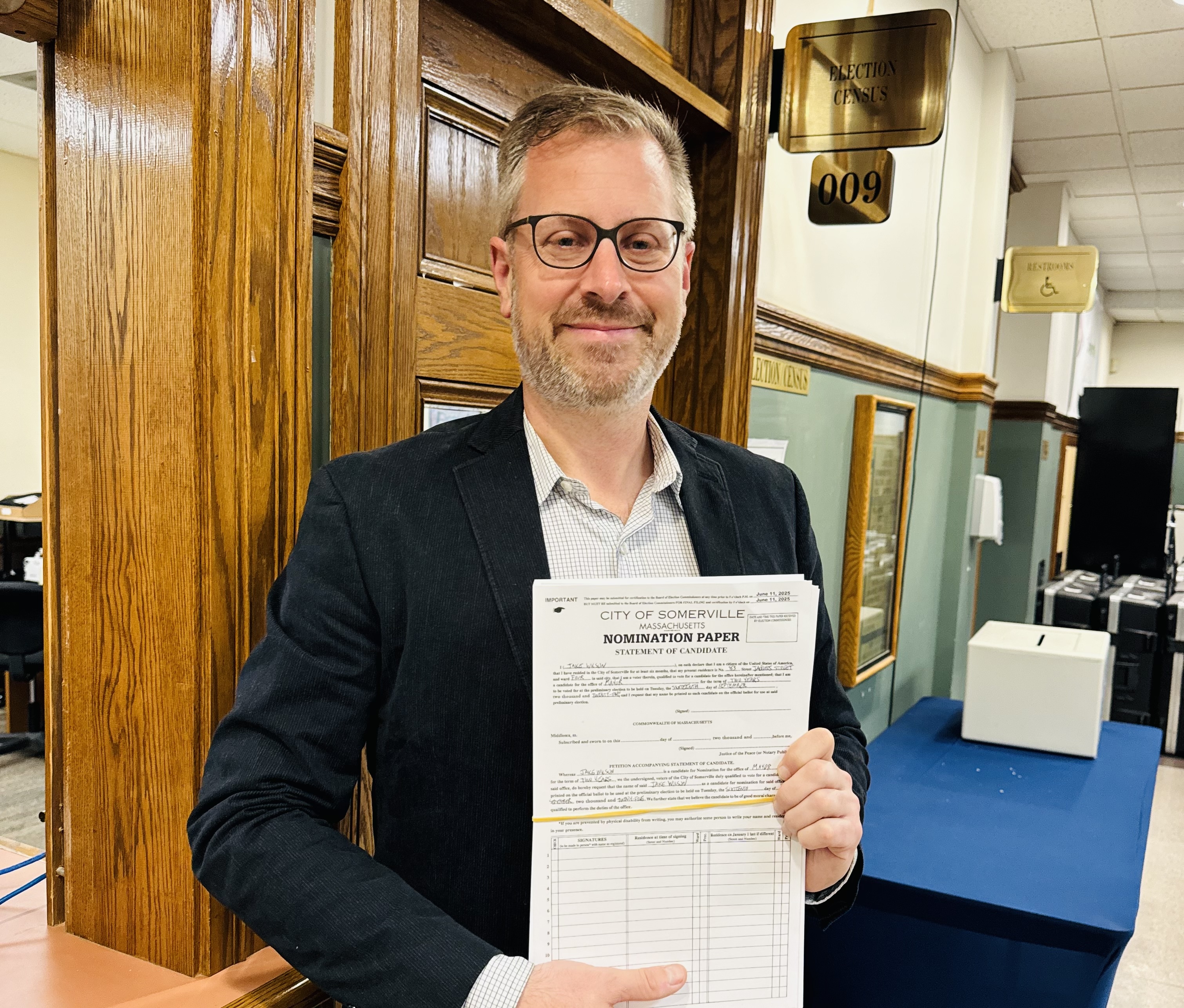 Jake holding nomination papers in front of a wooden door
