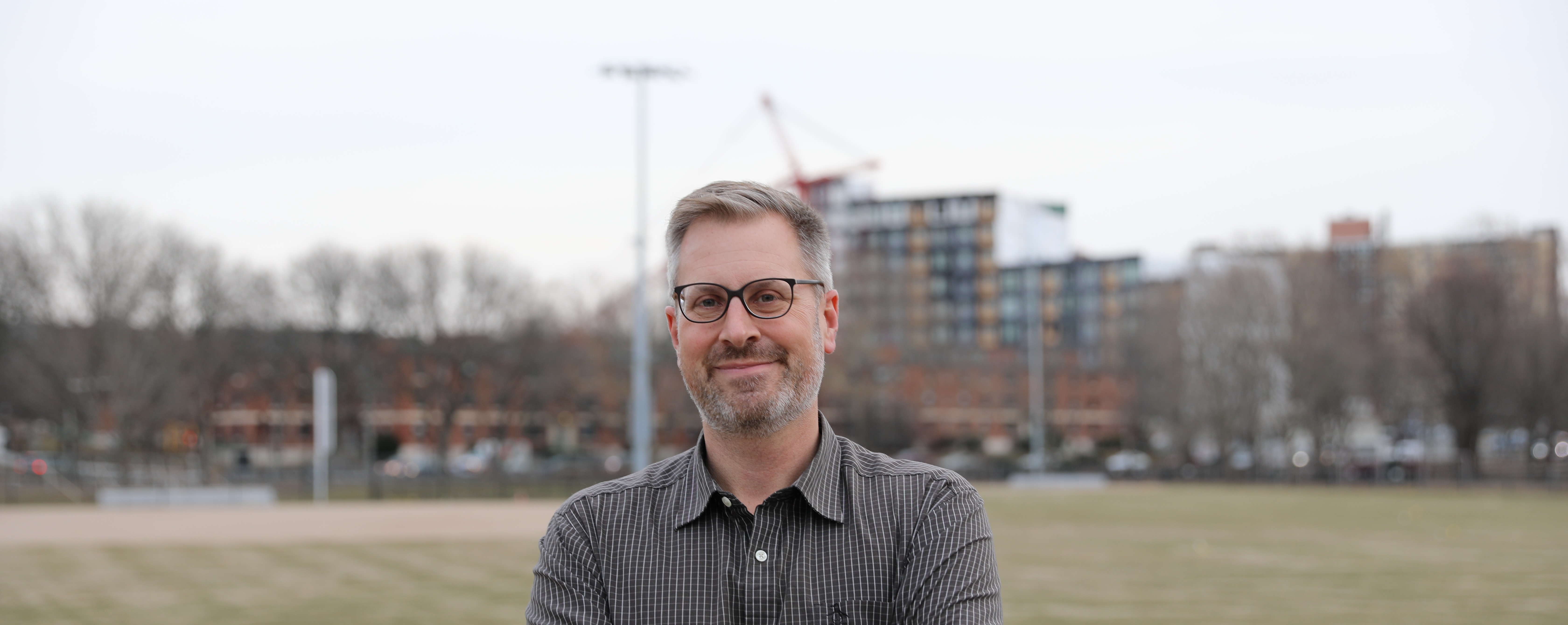 Jake poses in front of an open field and construction in the background