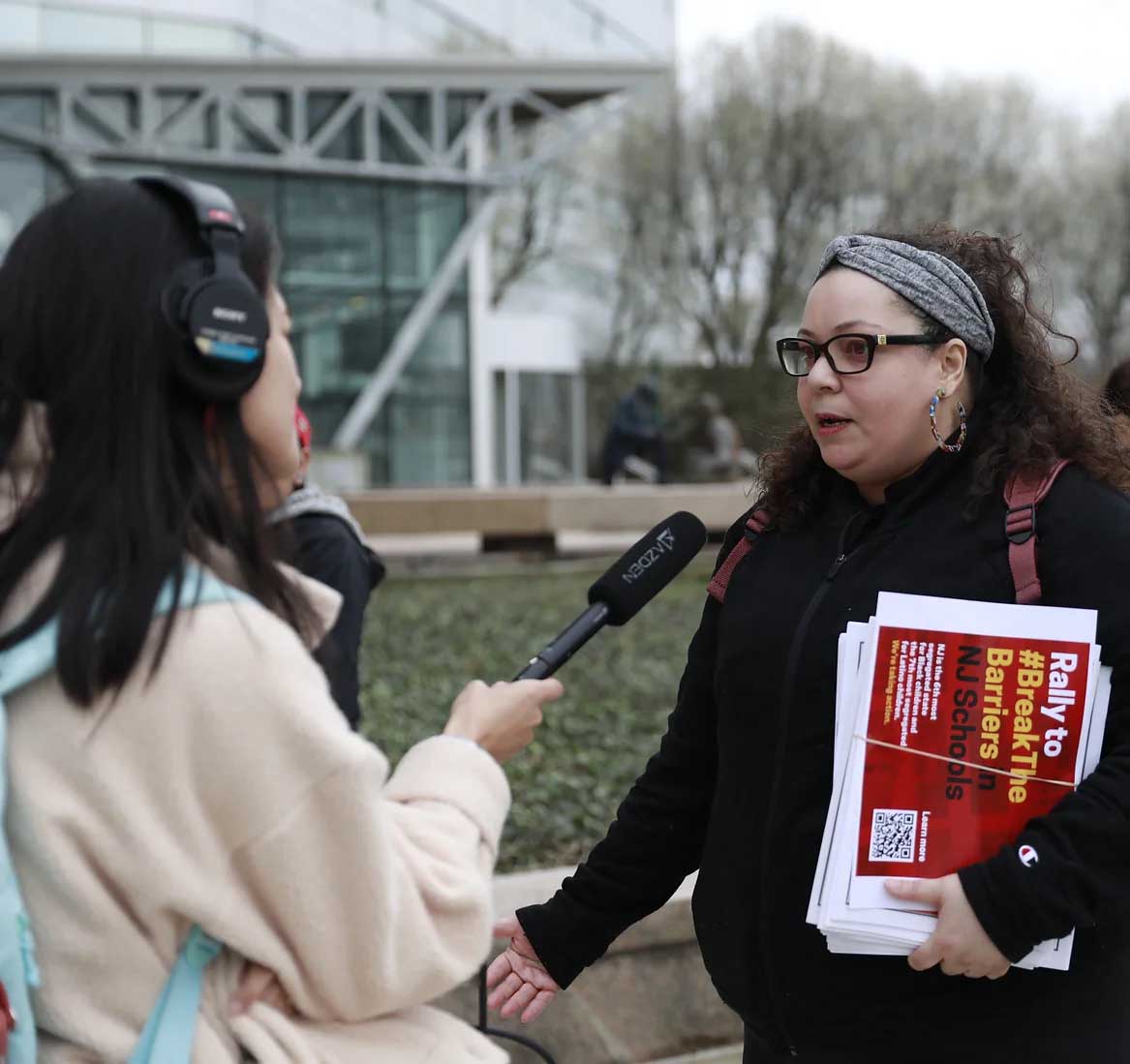 Latina woman with headband and glasses being interviewed in an outside setting