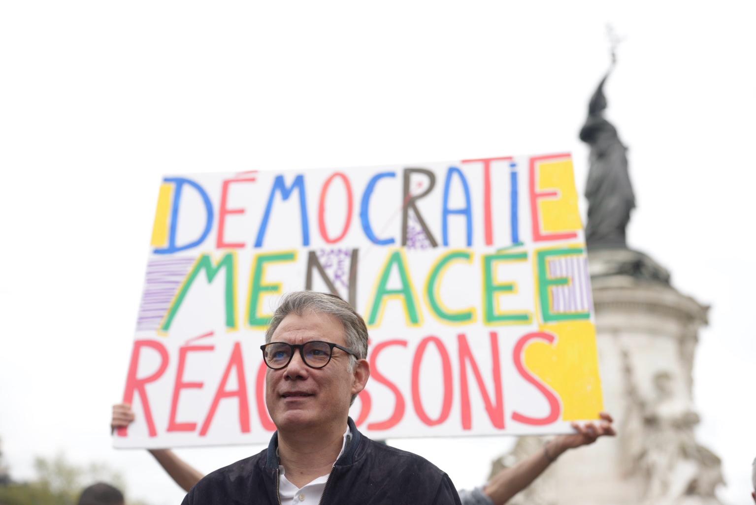 Olivier Faure à la Place de la République  (Paris) devant une pancarte affichant « Démocratie menacée :  Réagissons »