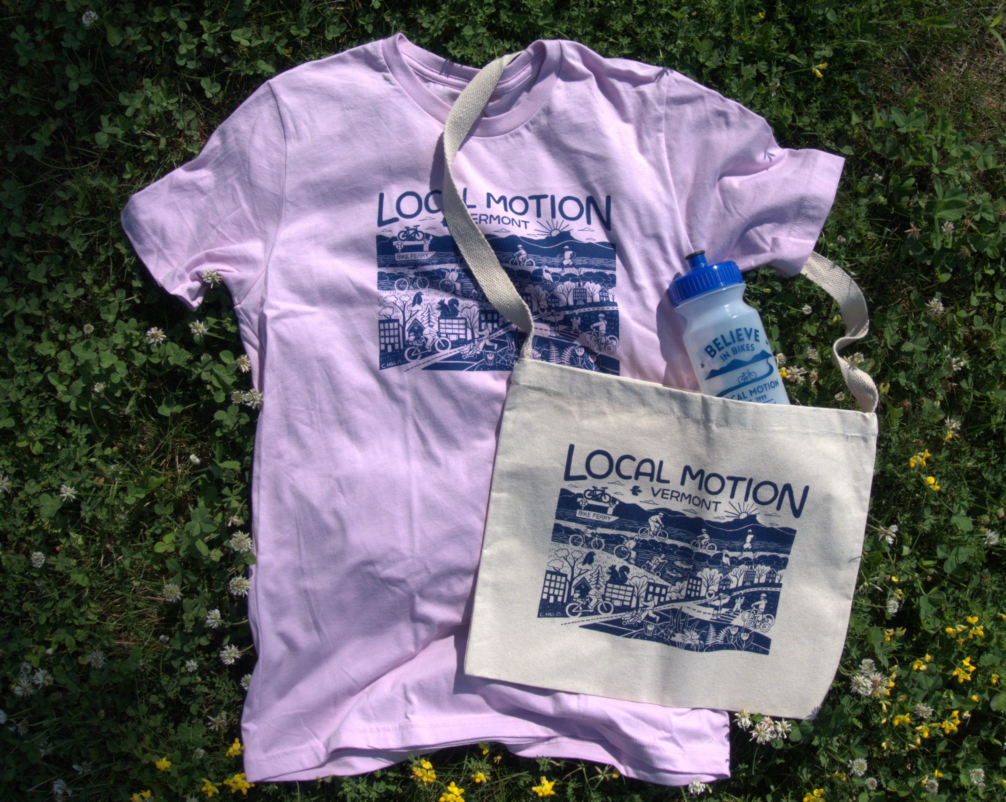 a pink t-shirt, a canvas bag, and a clear plastic water bottle all lay in a pile on the grass