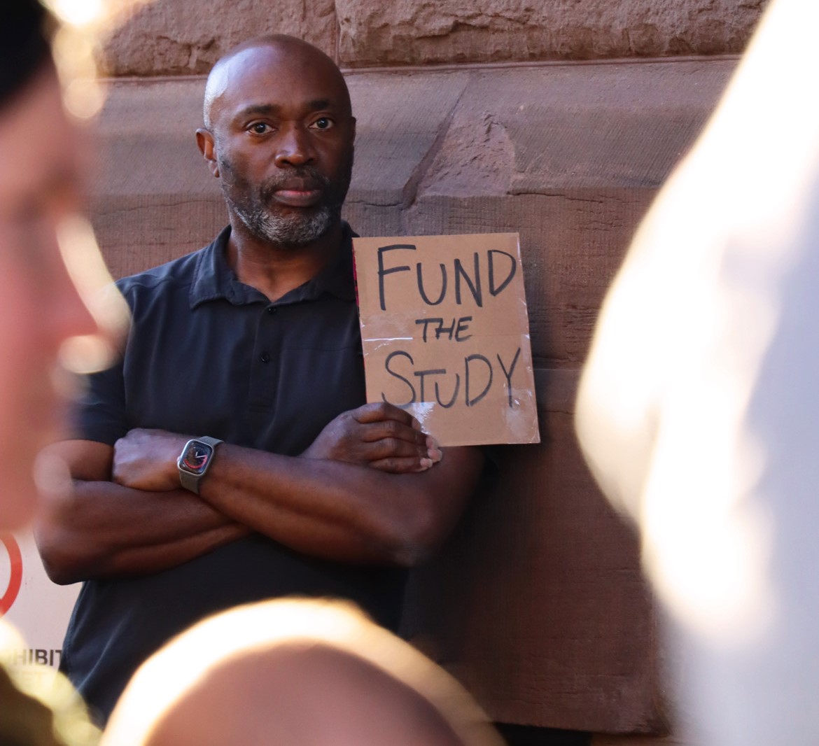 single man with Fund the Study sign