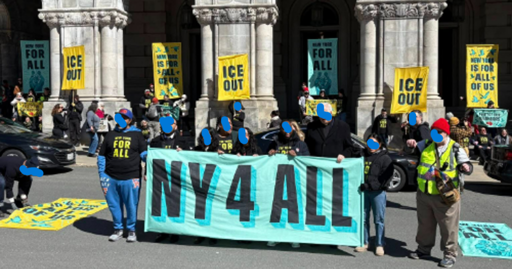 crowd on street with ny4all signs in front of capitol