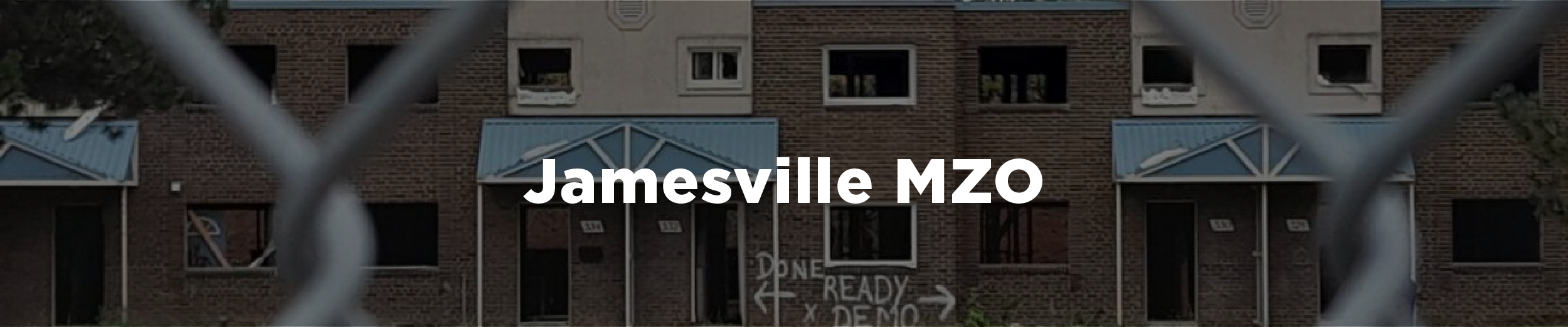 Image of the abandoned Jamesville townhomes shot through a chainlink fence in the fall