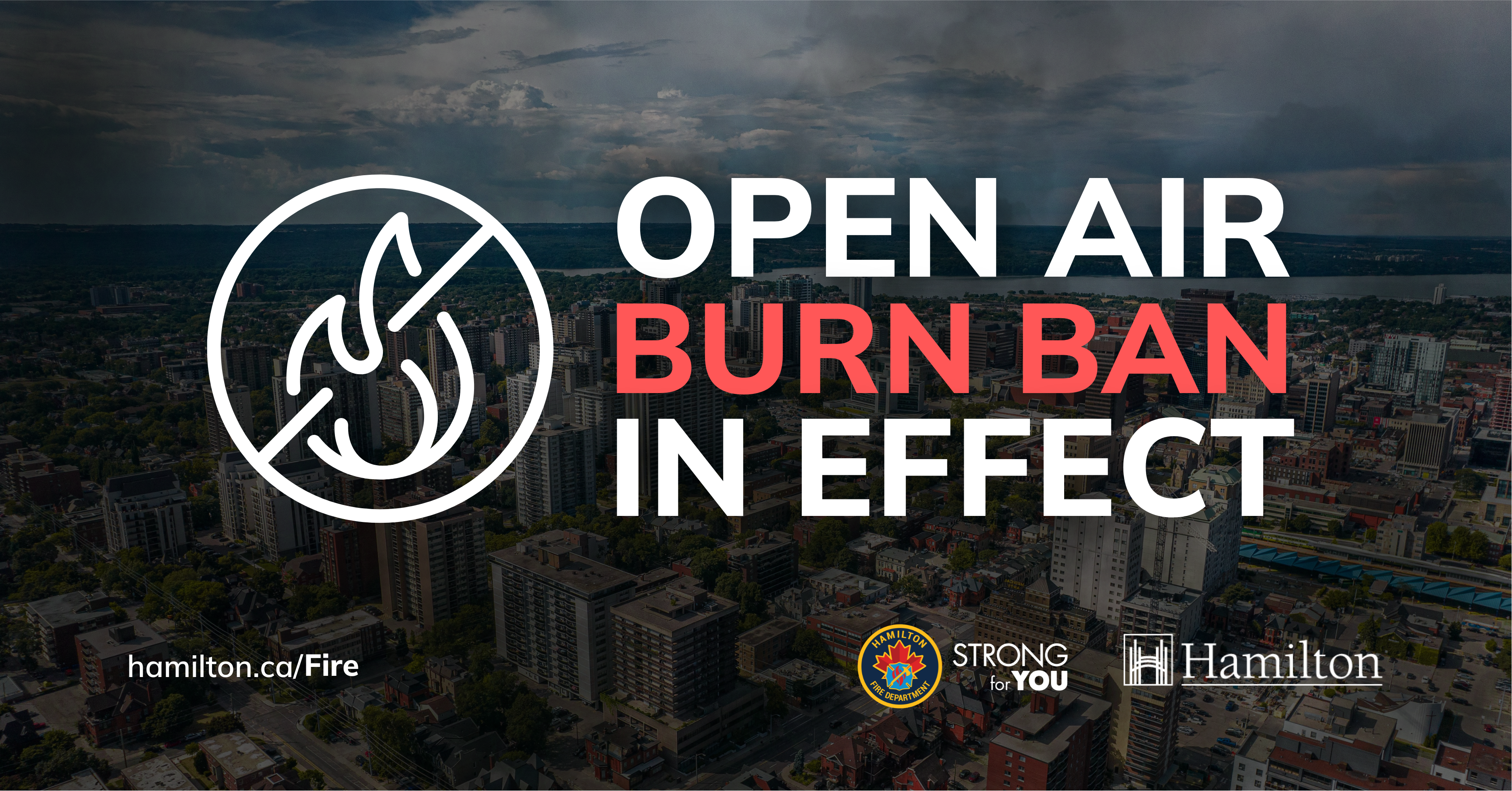 A shaded image of Hamilton from the air with the overlaid text "open air burn ban in effect" and a graphic of a small fire with an X through it