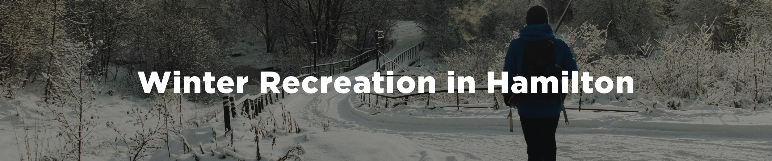 A man walking on a snowy road toward a bridge on a clear winter's day with the overlaid text "Winter Recreation in Hamilton"