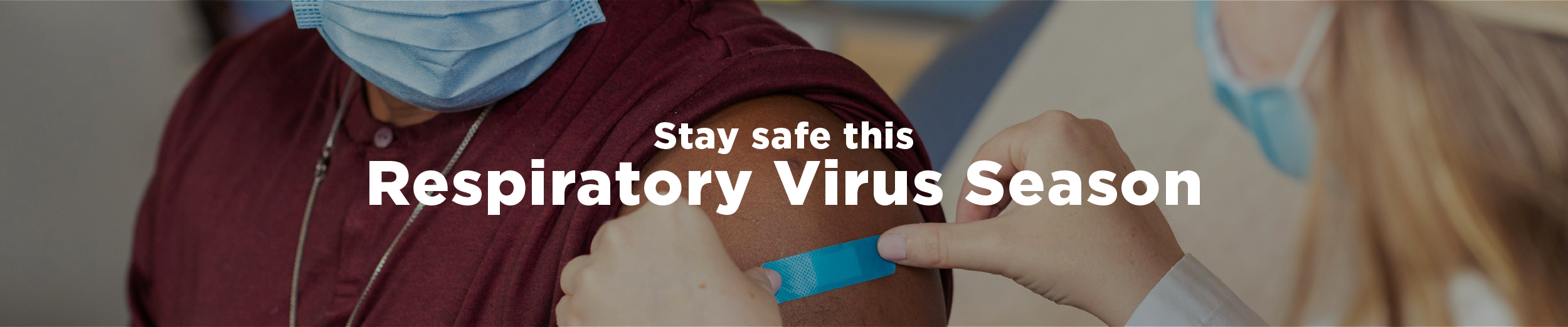 A medical professional in a white lab coat applies a blue bandage to the arm of a patient who has just received a shot with the overlaid text "Stay safe this respiratory virus season"
