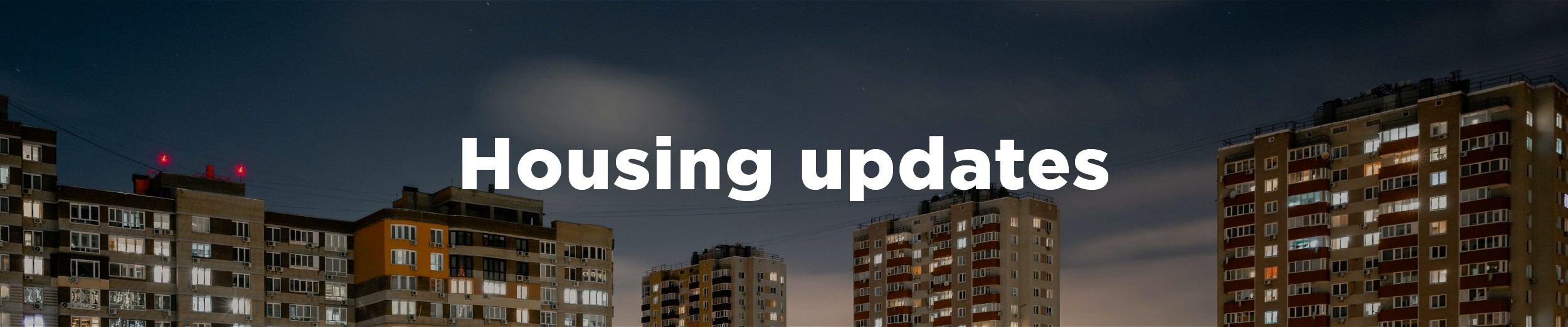 A series of apartment blocks at night with lit-up windows and the overlaid text "housing updates"