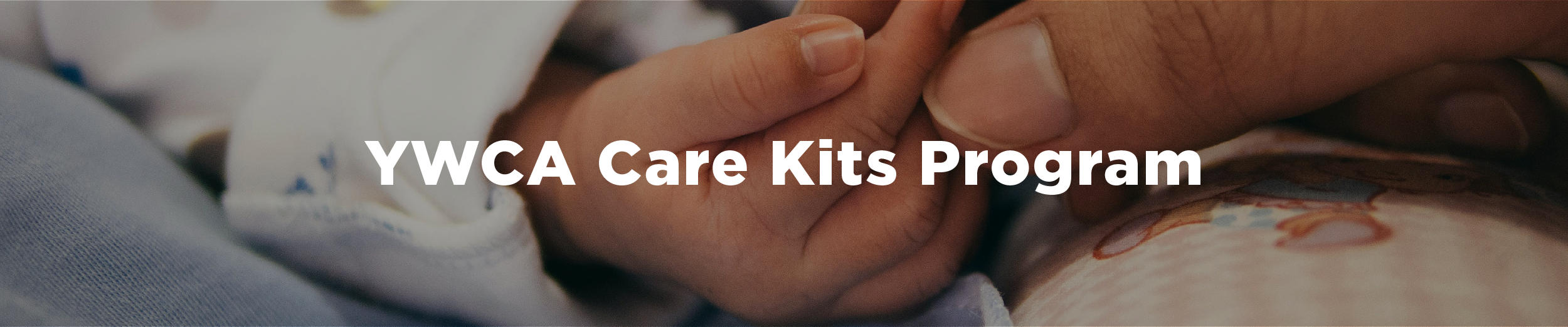 Image of a baby holding a person's finger with their hand and the overlaid text "YWCA Care Kits Program"