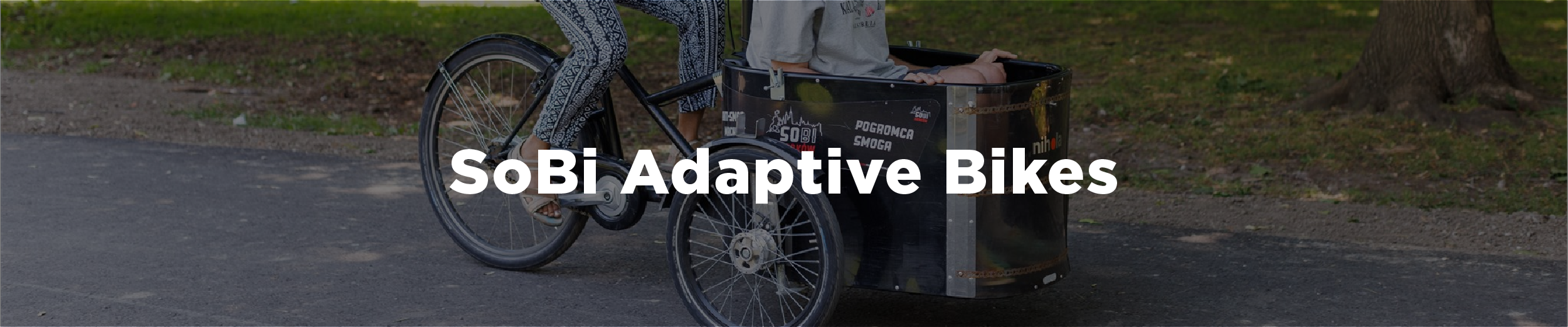 Image of a person peddling a bike that has a space in it for a passenger who is seated with the overlaid text "SoBi Adaptive Bikes"
