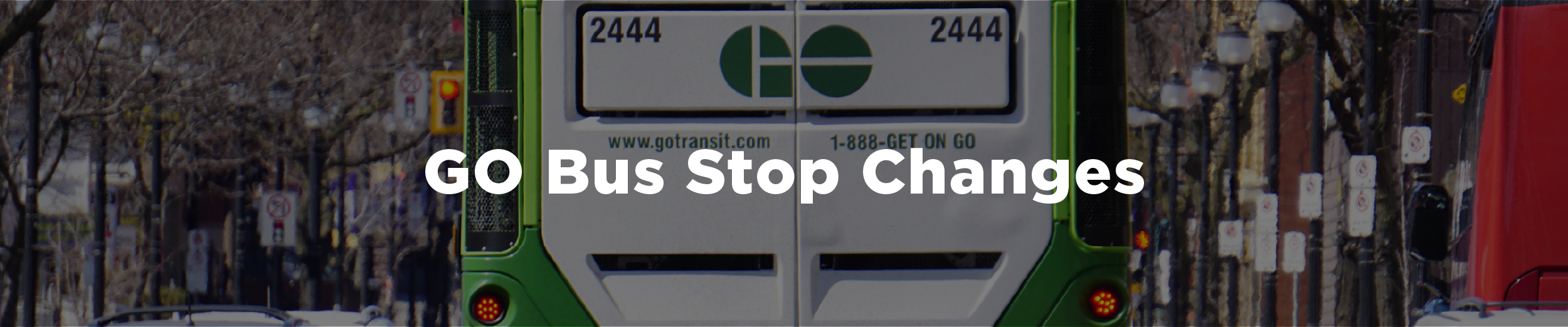 The back of a GO bus traveling westbound in downtown Hamilton in the winter with the streetscape unfolding on either side of the bus and the overlaid text "GO Bus Stop Changes"
