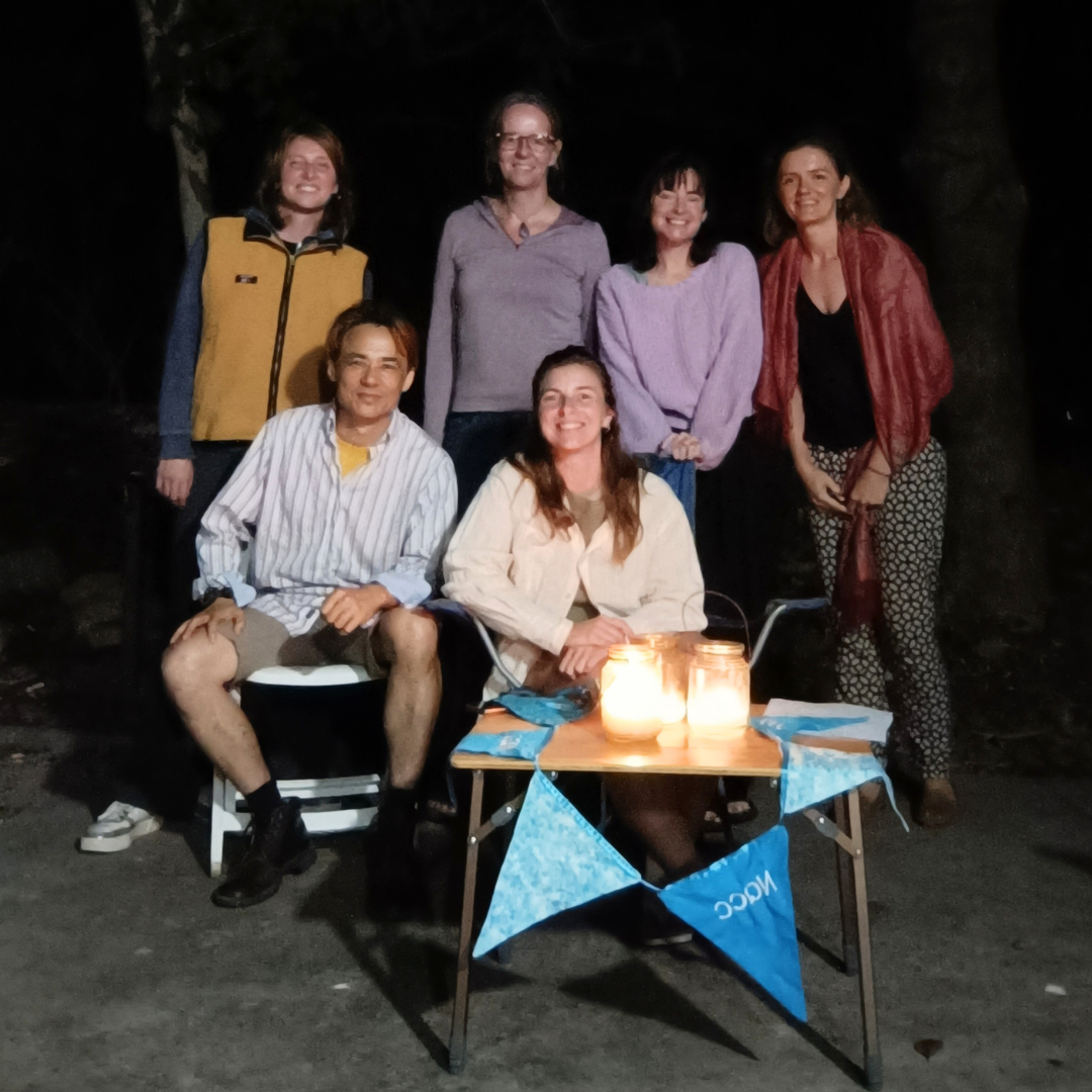Group of people posing for people around a camping table and candles