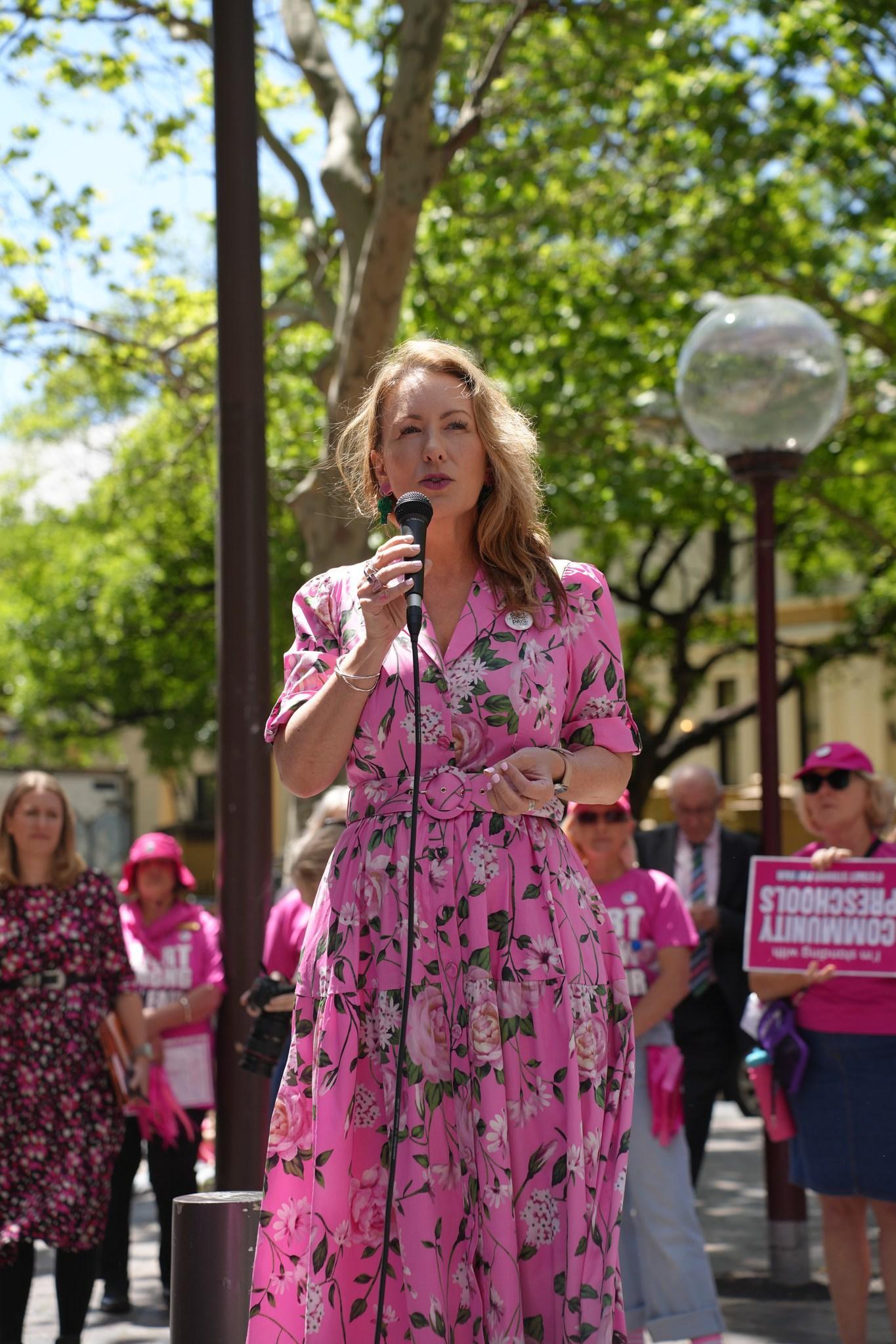 Abigail speaking at a rally while wearing a pink dress