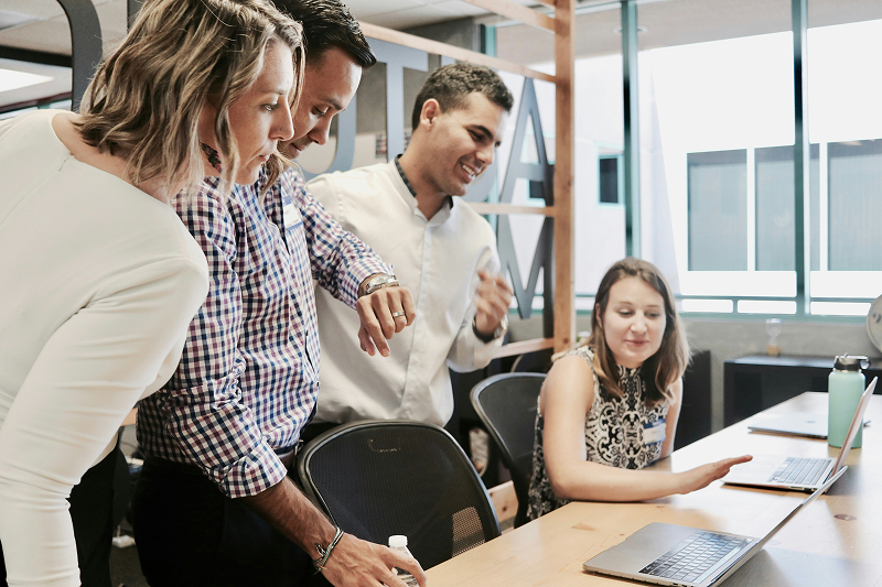 People standing over laptop