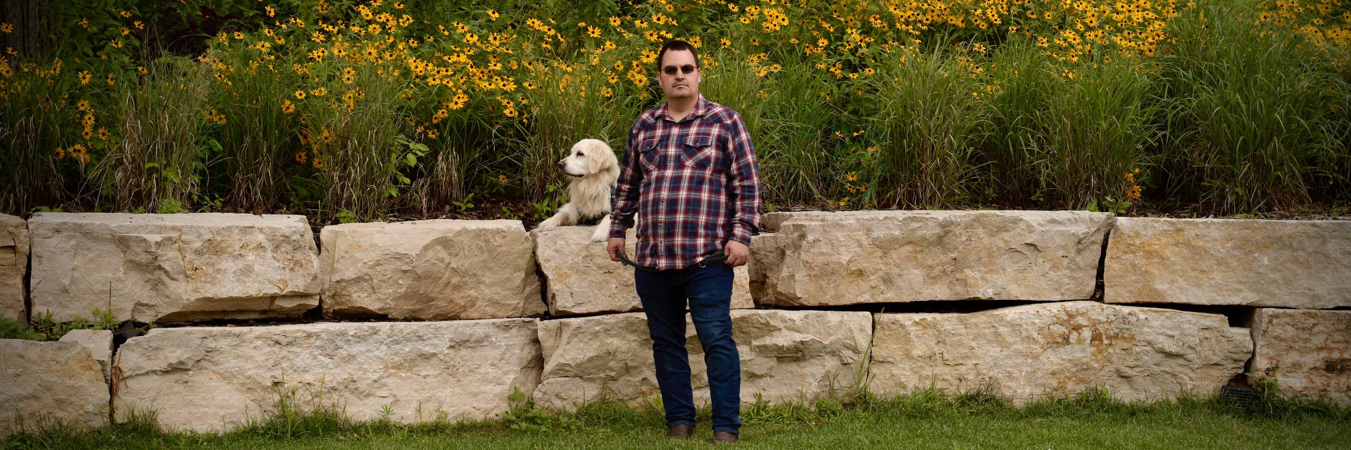 Veteran with service dog posing along wall