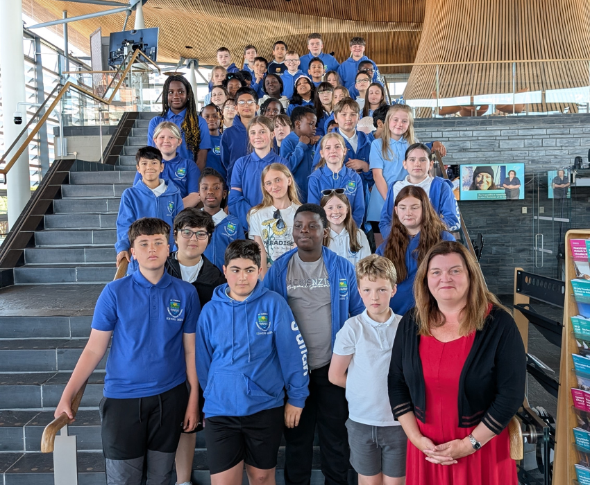 Sioned Williams is standing with pupils from St Thomas Community Primary School on the steps inside the Senedd