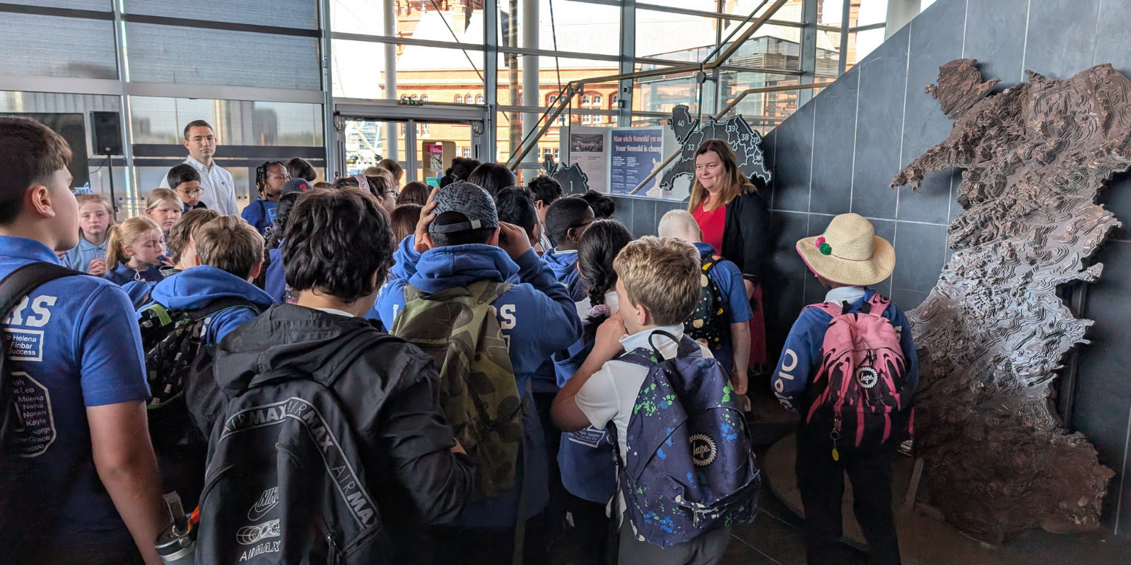 Sioned Williams is talking to pupils from St Thomas community school. They are stood inside the Neuadd inside the Senedd.