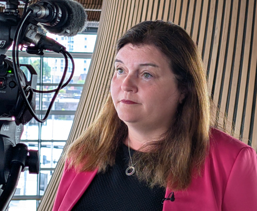 Sioned Williams MS is in the Senedd Oriel being interviewed, with the camera visible to the left of the photo.