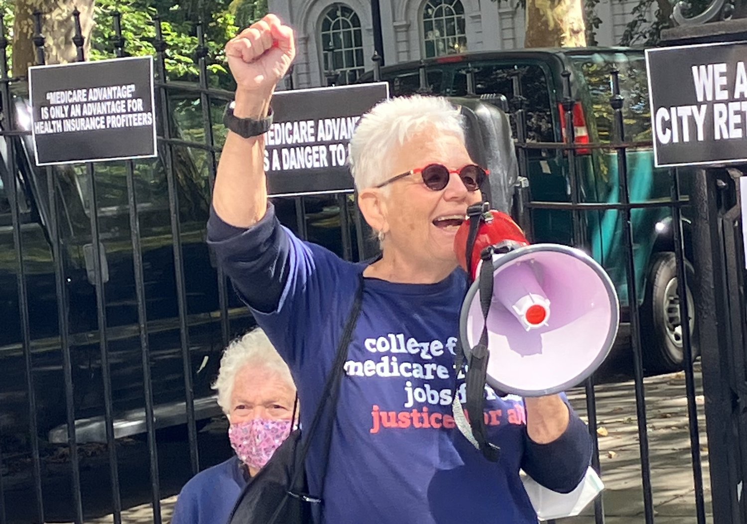Julie speaking into a bullhorn at a rally, wearing a blue \