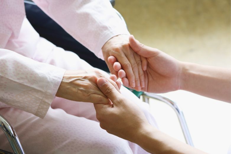 Child in wheelchair holding hands with adult